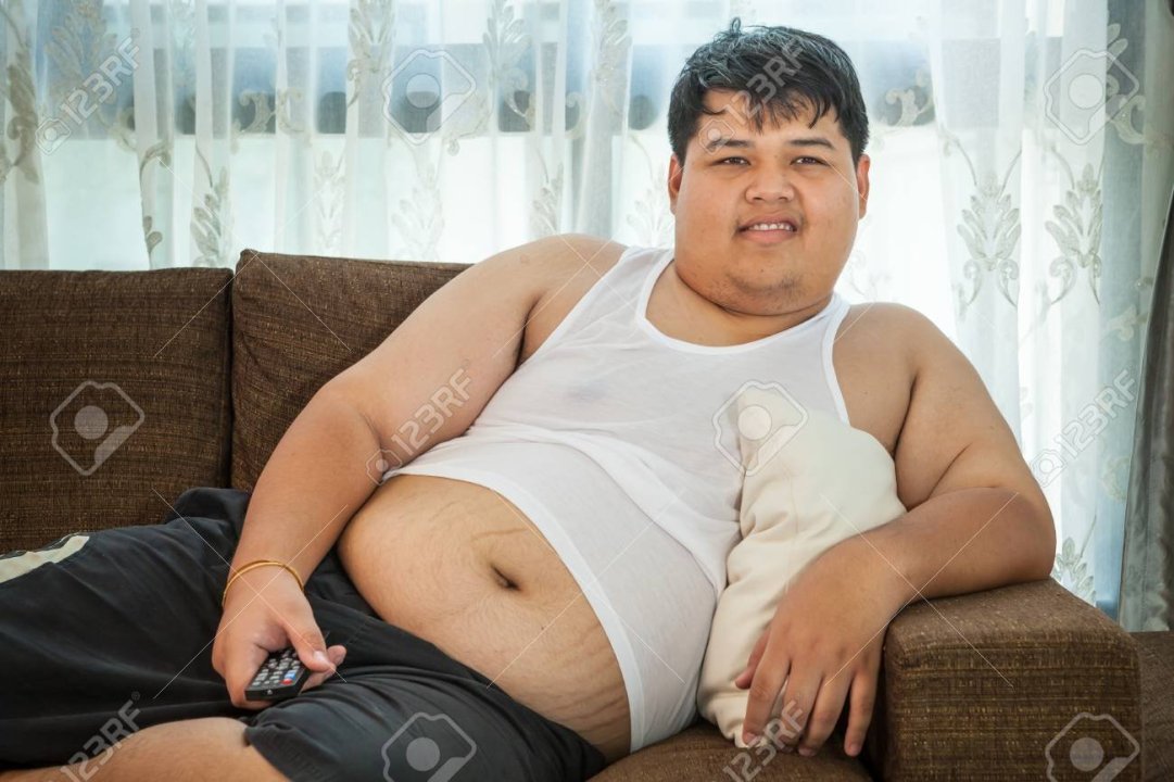 39304844-overweight-asian-guy-sitting-on-the-couch-with-remote-in-hand-trying-to-watch-some-tv.jpg